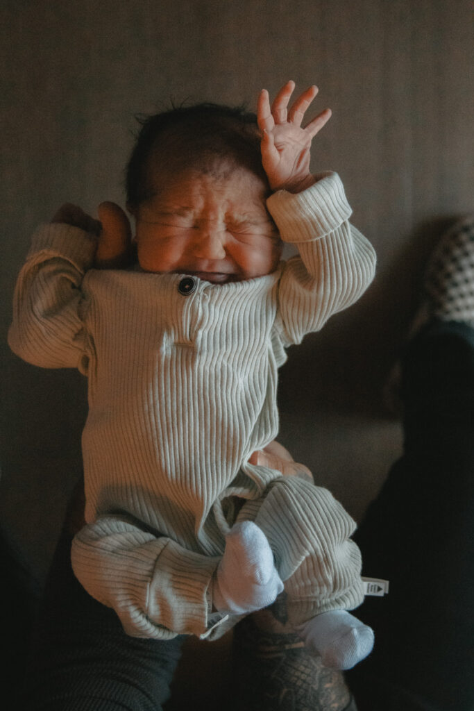 baby boy in onesie being held by dad one day after birth