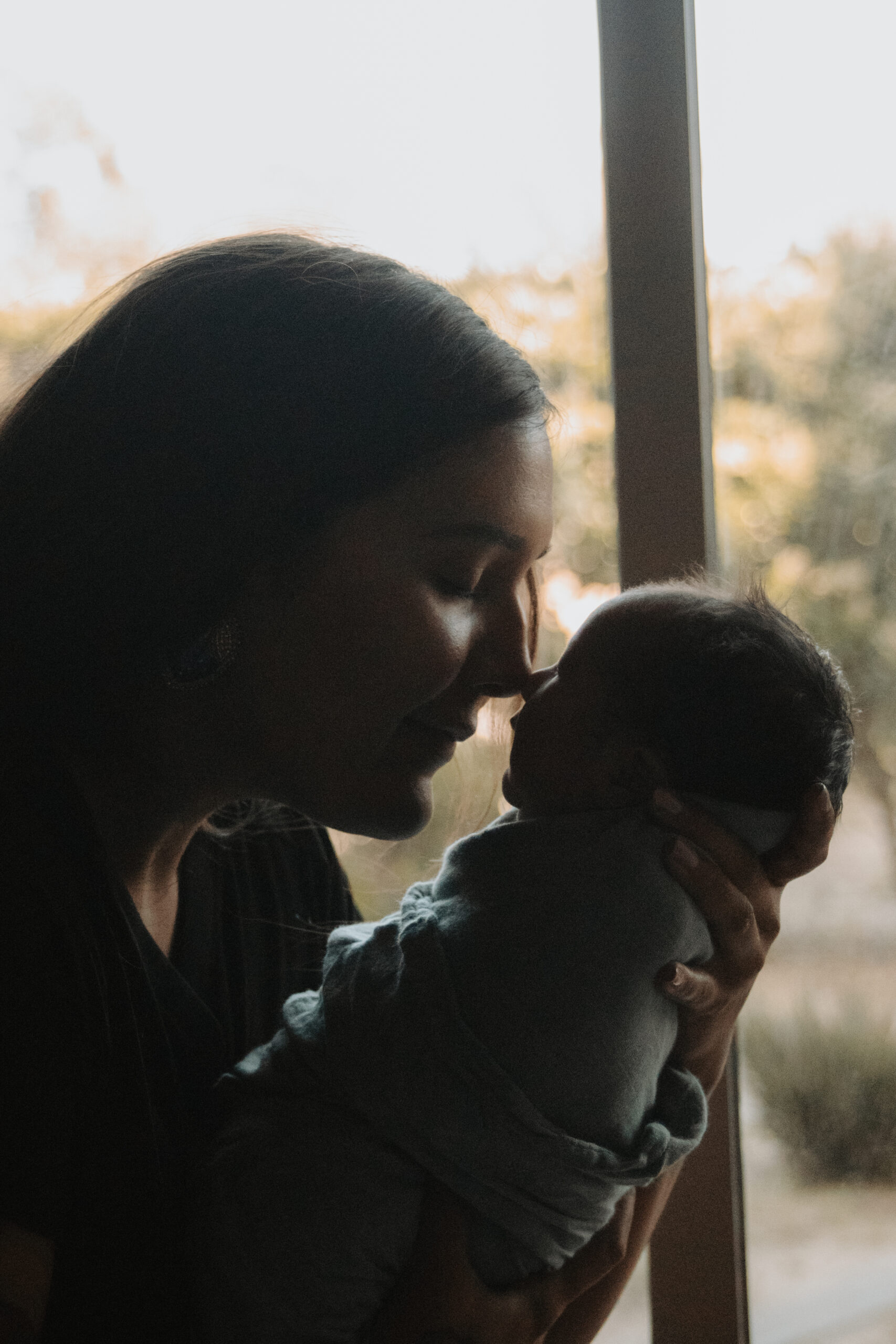 intimate moment of mom and baby boy nose to nose in front of window